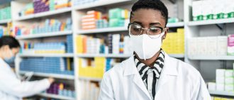 Female pharmacist with face mask working at pharmacy